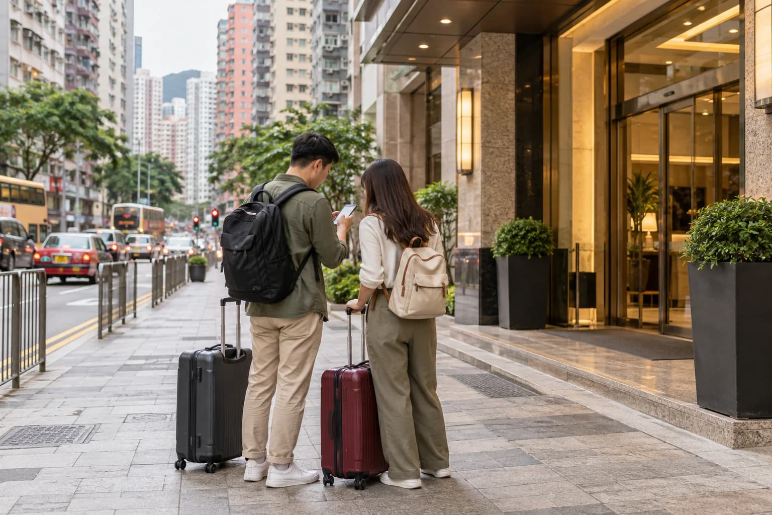 Illustrative hotel arrival scene: two travellers with suitcases checking an address on a phone on a city pavement