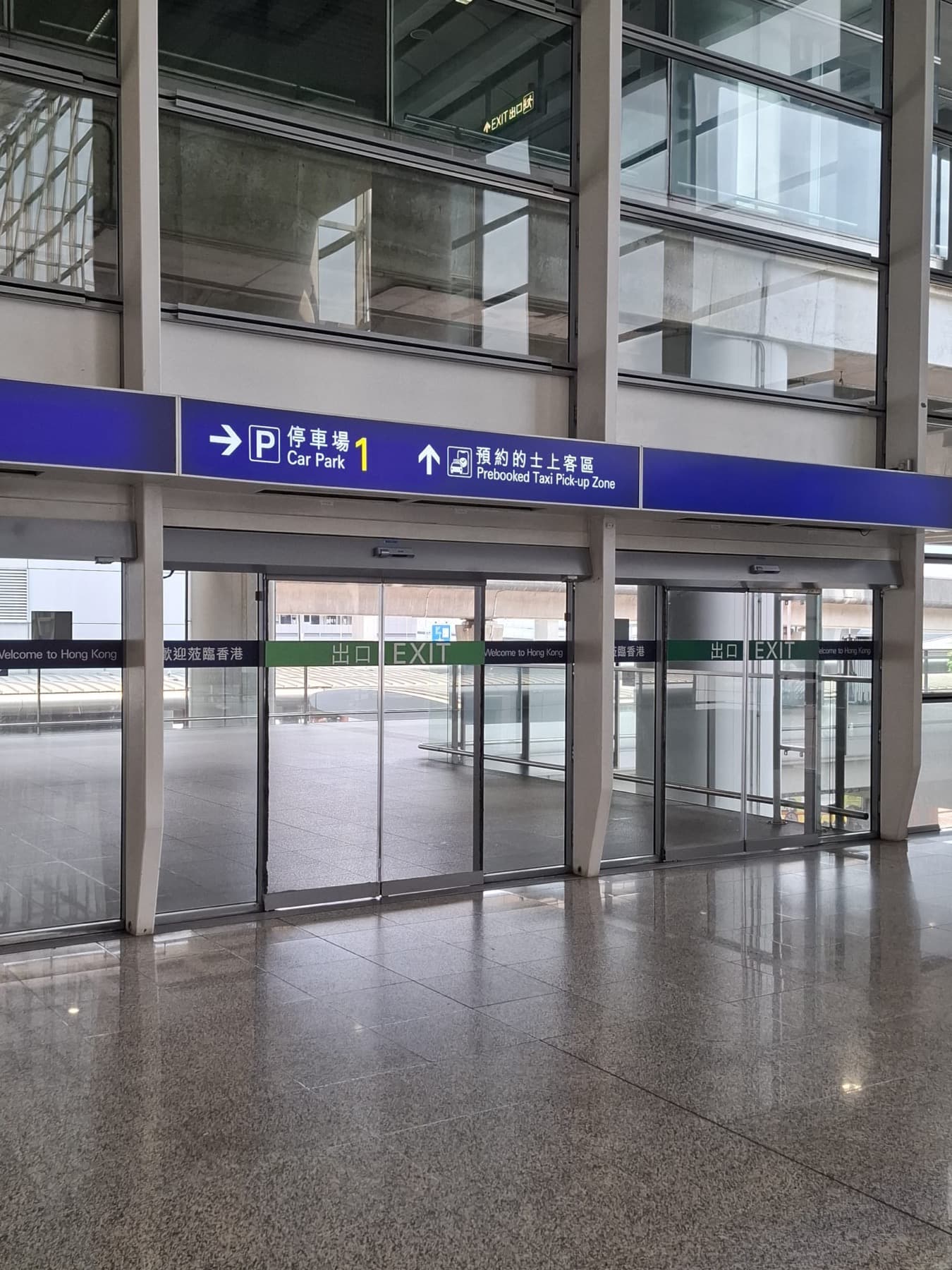 玻璃門上方嘅「停車場1」及「預約的士上客區」中英文指示牌